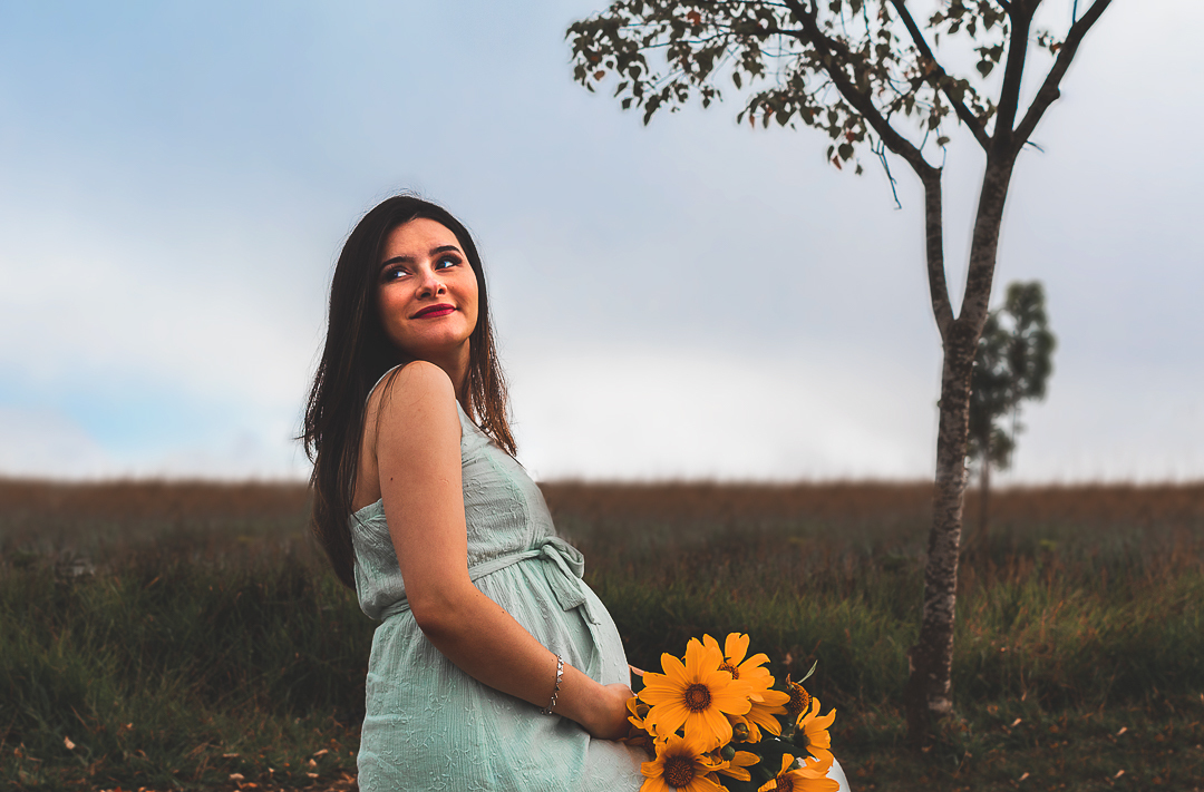 Gestante com boquê de flores amarelas
