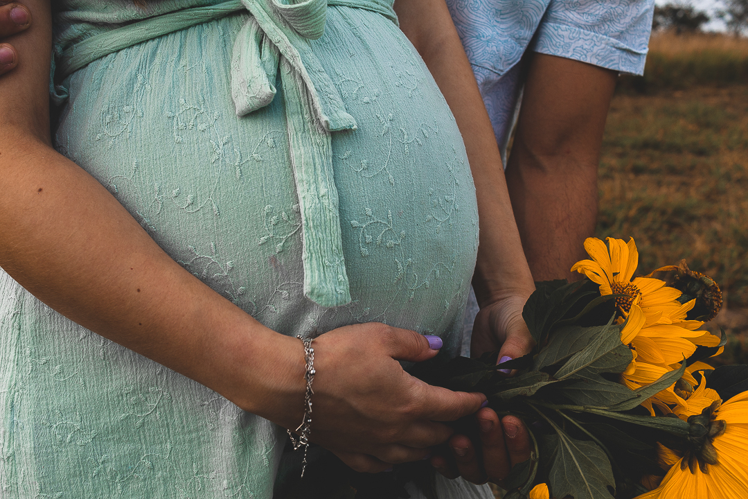 barriga de gravida, junto com buquê de flores amarelas 