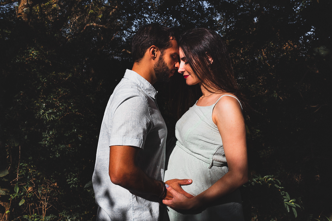 casal gestante, com mãos na barriga, na floresta
