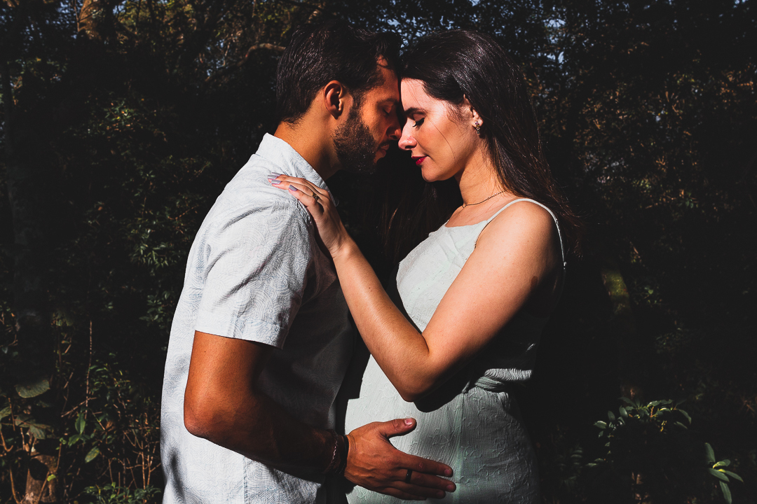 casal gestante, com mãos na barriga, na floresta