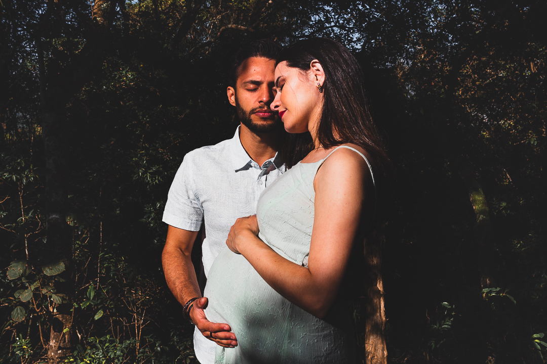 casal gestante, com mãos na barriga, na floresta