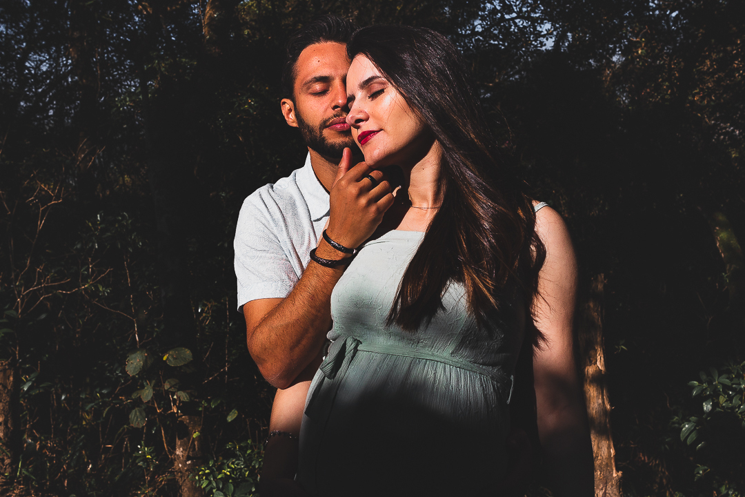 casal gestante, com mãos na barriga, na floresta