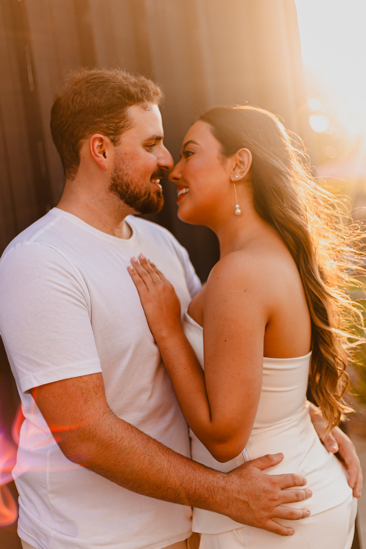 Casal em ensaio fotográfico com paisagem da Orla do Guaíba ao fundo.
