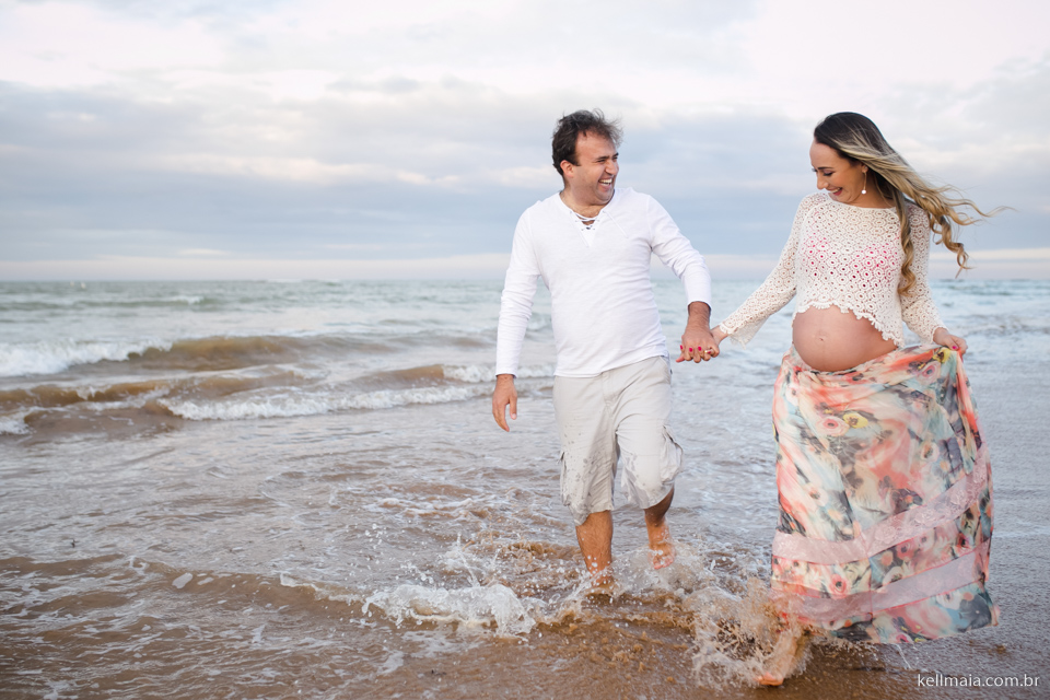 gestante com esposo andando na praia, na água