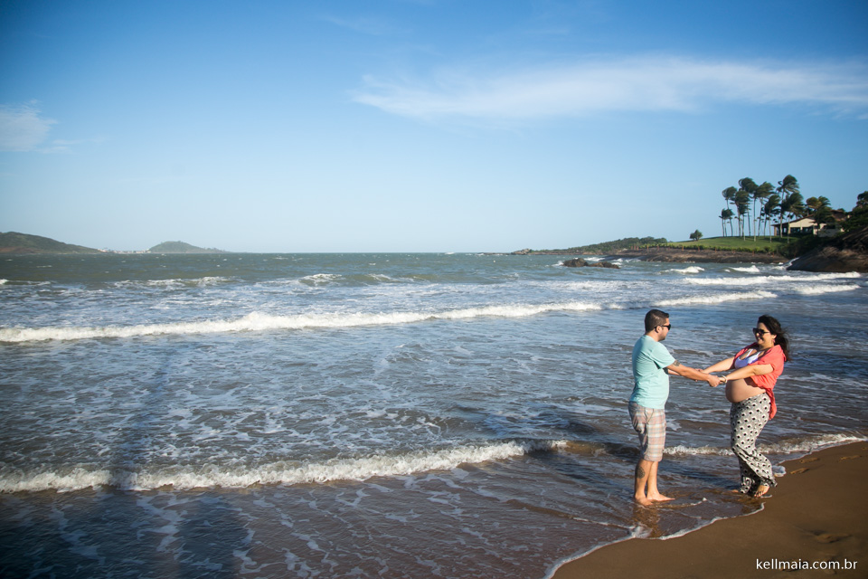 casal de grávida e esposo na praia