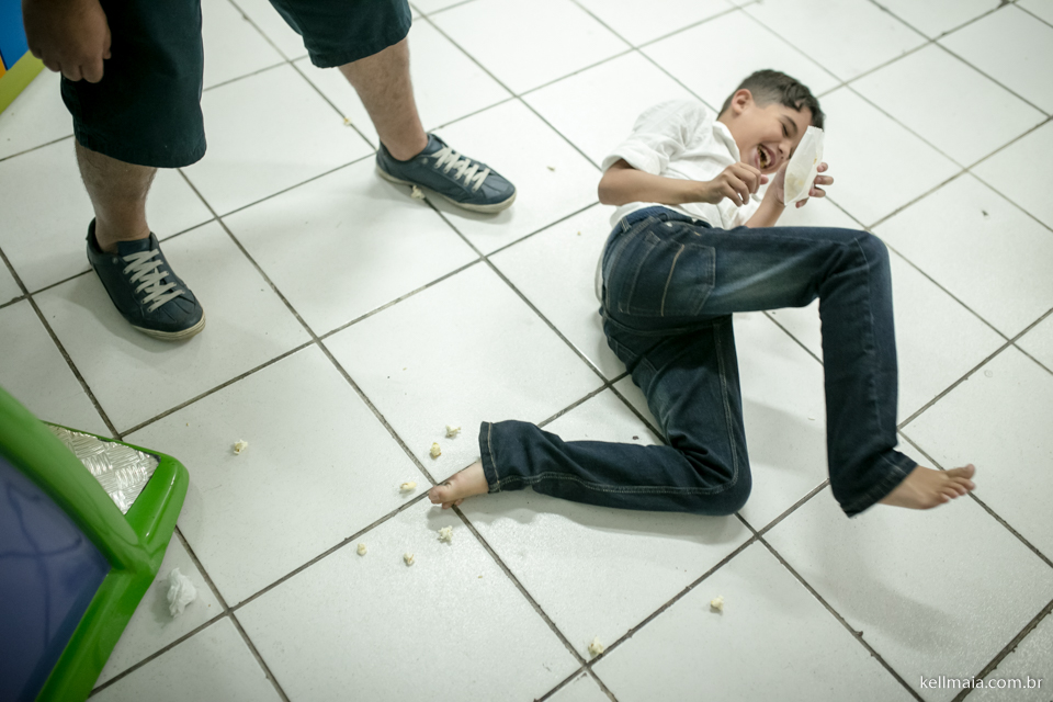 criança rindo no chão, durante o niver