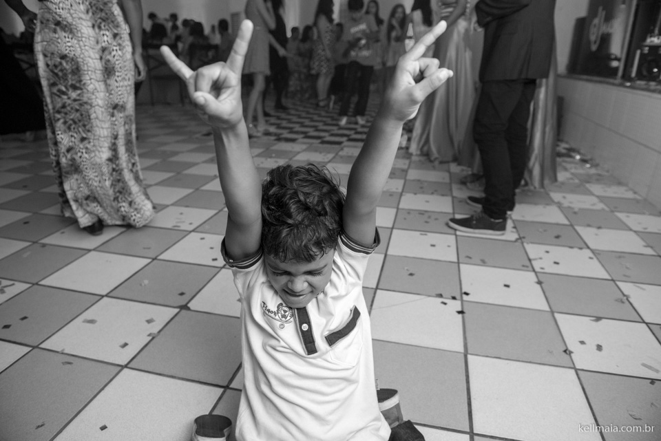 criança no chão fazendo gesto rock and roll