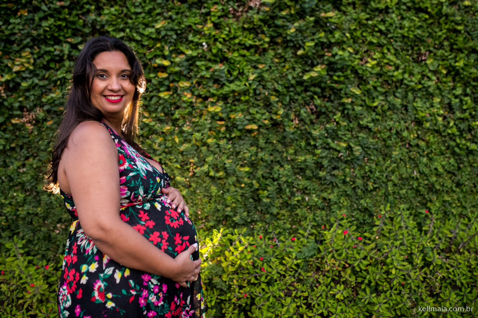 grávida no muro de plantas