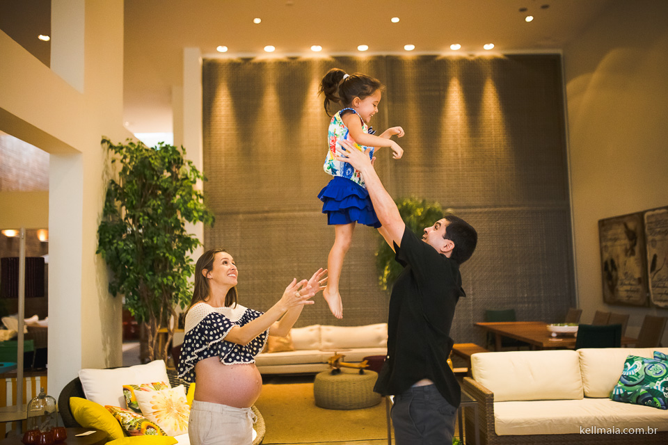 Papai jogando a filha pro alto e grávida observando
