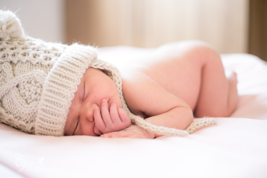 fotografia recém nascido com capuz bege claro sob manta rosa