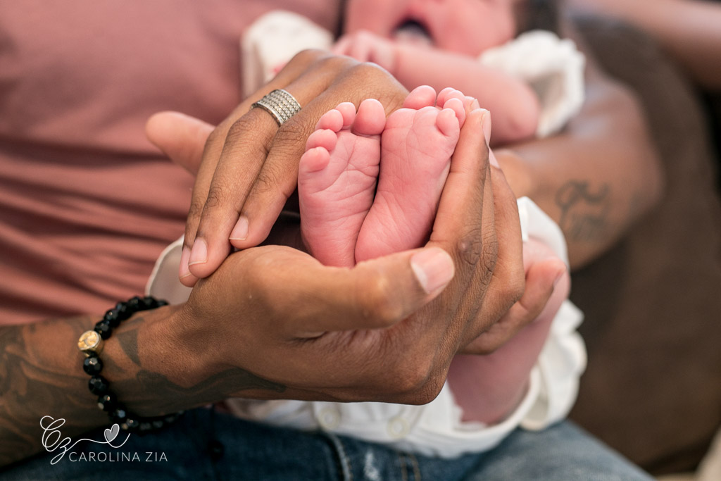 Pé de recém nascido envolvido nas mãos do pai