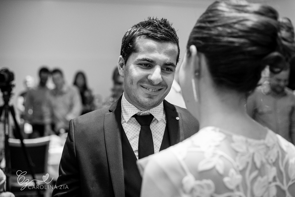 Noivo olha sua esposa com carinho durante cerimônia de casamento.