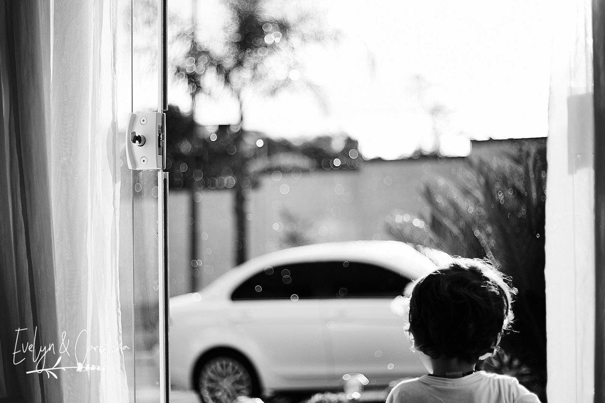 enquanto a chuva cai, menino observa a chuva e o dia