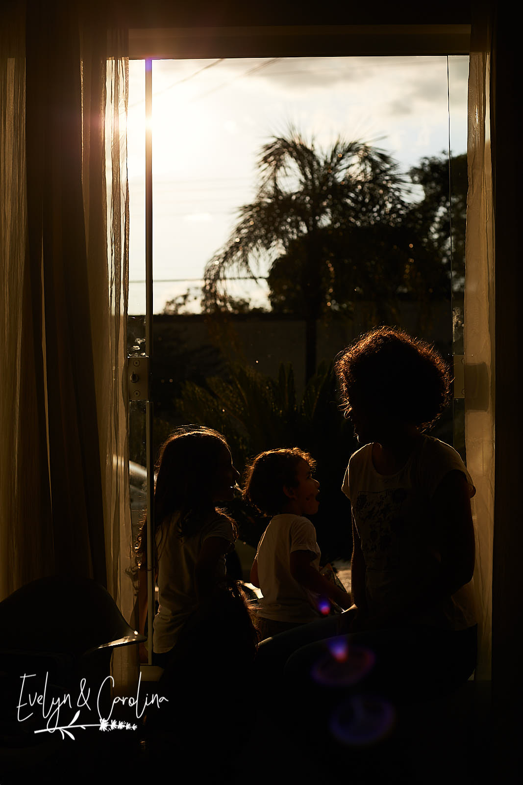 por do sol amarelo em janela grande. Crianças interagem com adulto