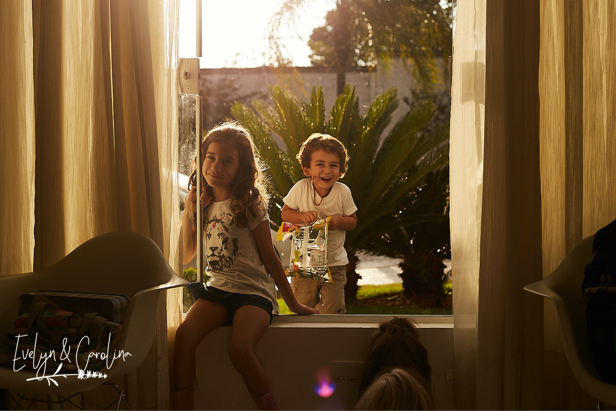 menino brinca na chuva enquanto sua irmã faz pose para a câmera. Cachorro shih-tzu observa as crianças