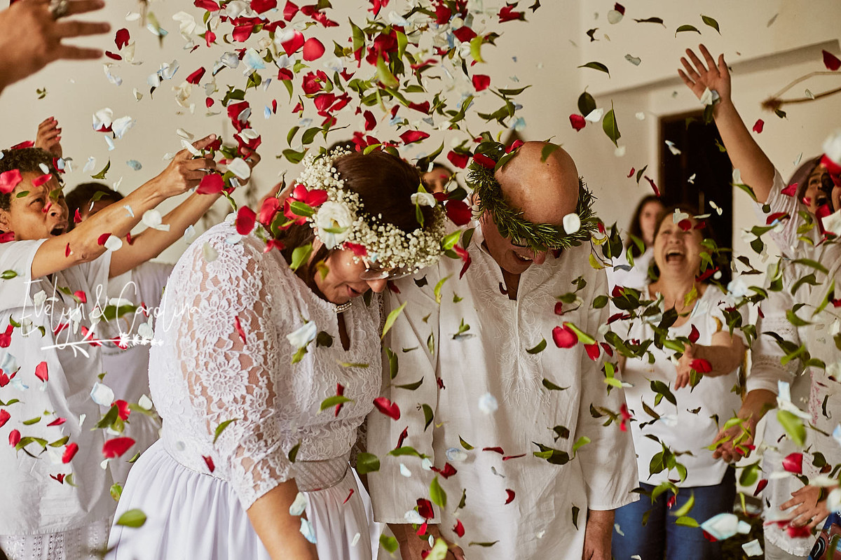 noivos recebem chuva de folhas e pétalas após a celebração de seu casamento na Umbanda.