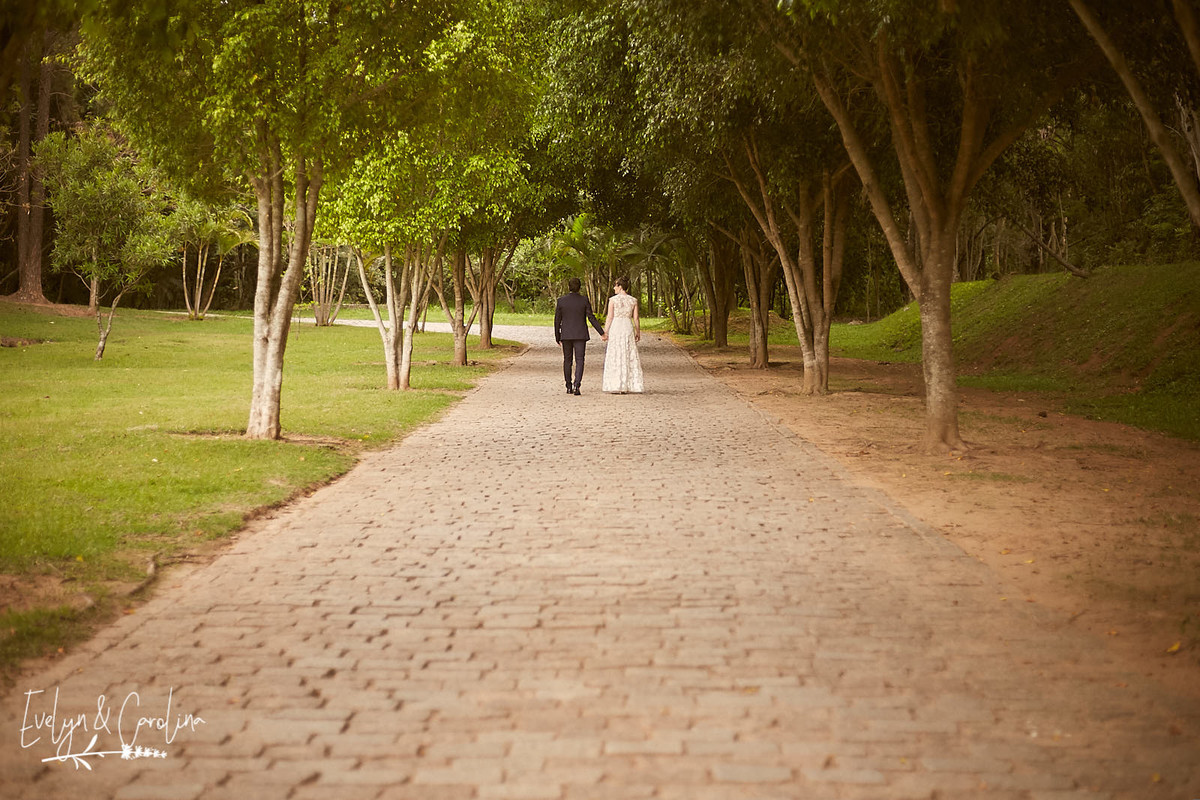 Foto de casal andando em estrada de pedra entre árvores noiva de branco em ensaio no interior de São Paulo Itatiba