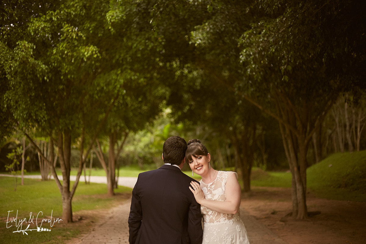casamento no campo noivos em paisagem de árvores e estrada de pedras noiva vestida de off White e noivo de terno azul escuro
