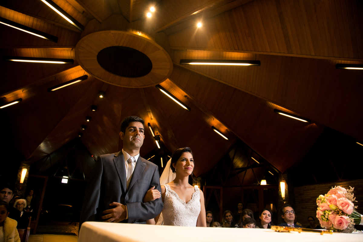 noiva e noivo sorriem ao escutar palavras do padre