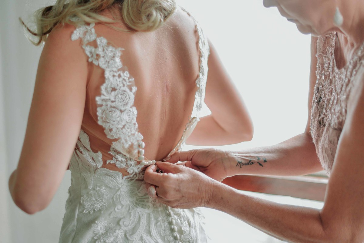 mae ajudando a noiva a colocar o vestido