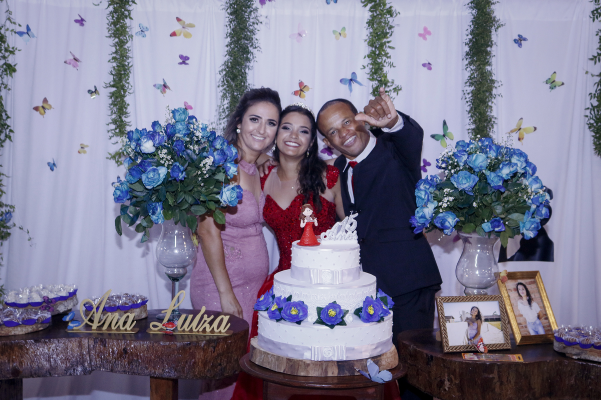 Foto da Ana Luíza com seus pais atrás do Bolo de 15 anos