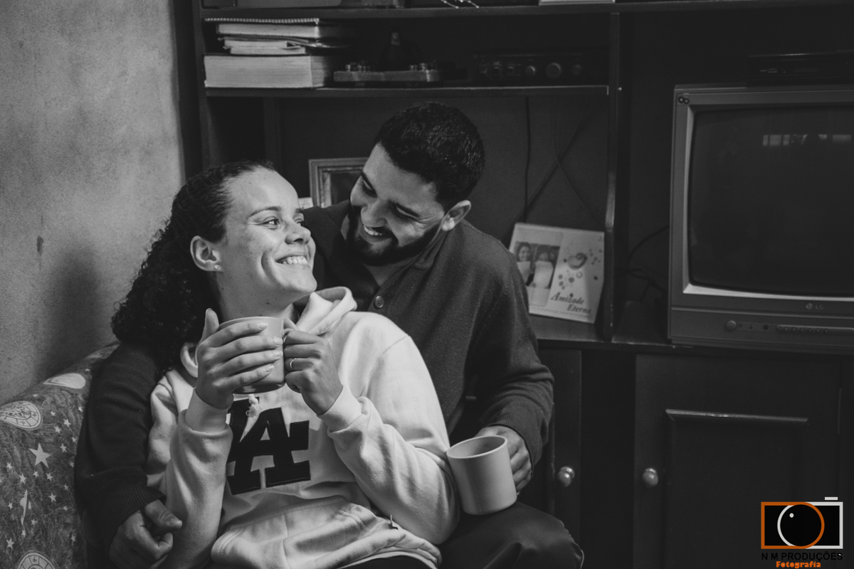 Casal Marina e Welington no sofá tomando café sorrindo