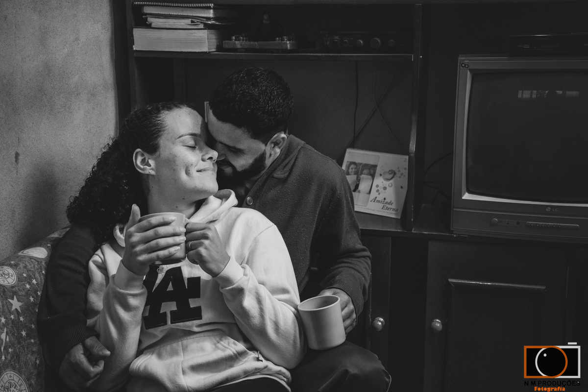 Casal Marina e Welington no sofá tomando café com olhar carinhoso