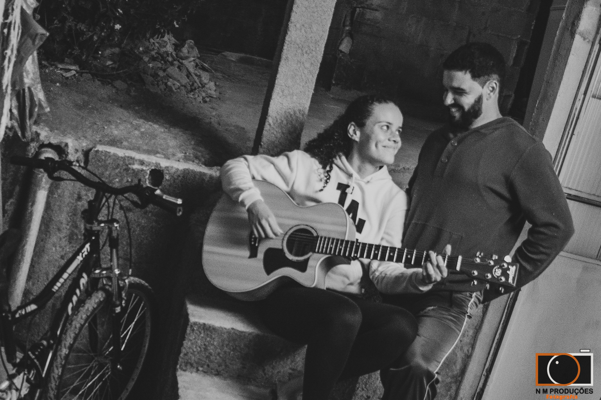 Casal Marina e Welington na varanda tocando violão sorrindo