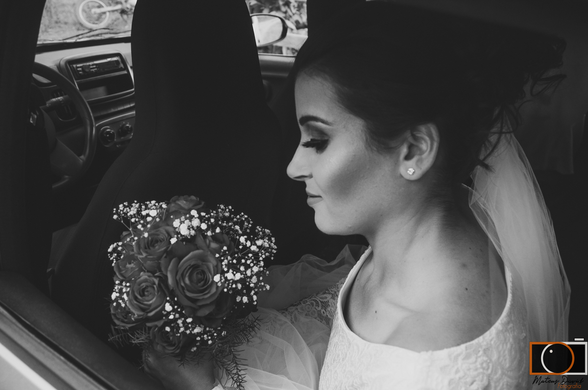 Casamento de Caroline e Adilson noiva no carro olhando buquê