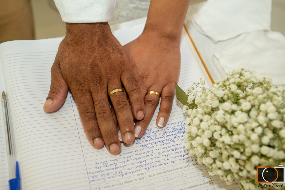 Casamento civil de Fabiola e Rodrigo mãos sobre o livro registro civil