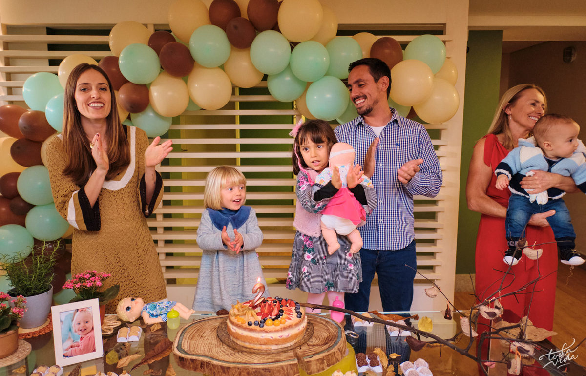 a hora do parabéns, família reunida em frente ao bolo de aniversário
