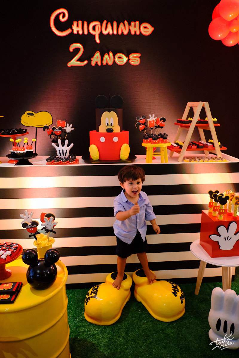 Aniversariante Chiquinho fibrando em frente a sua mesa decorada com tema Mickey Mouse no centro de Florianópolis