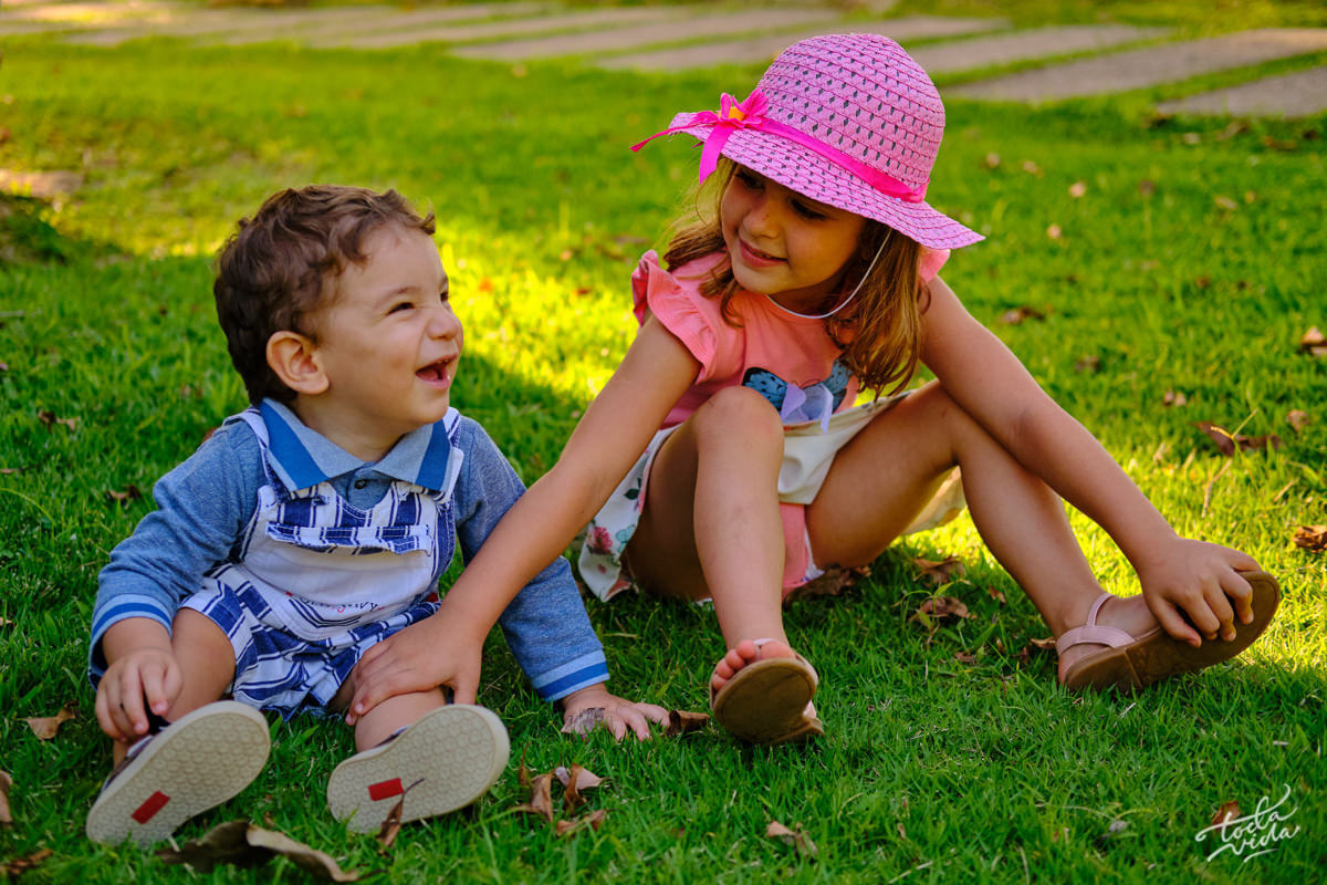 casal de irmãos brincando na grama em ensaio família