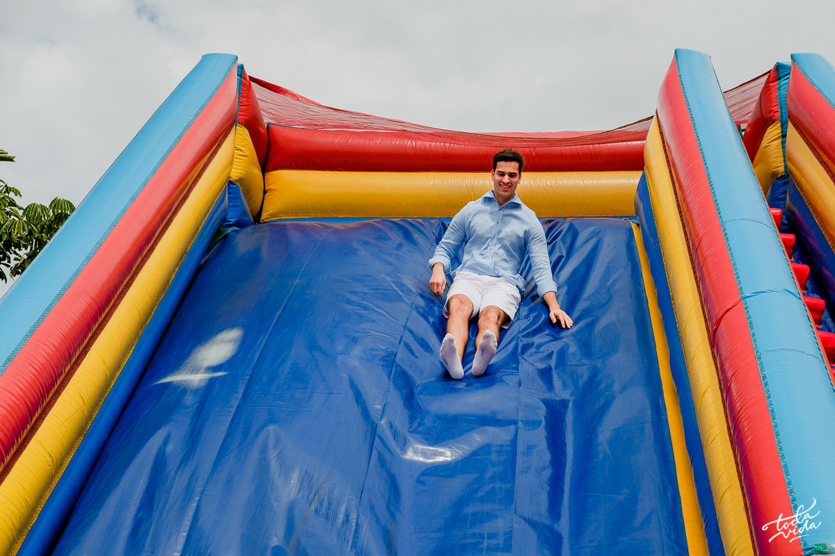 pai Eduardo brincando no escorregador na festa infantil de seu filho