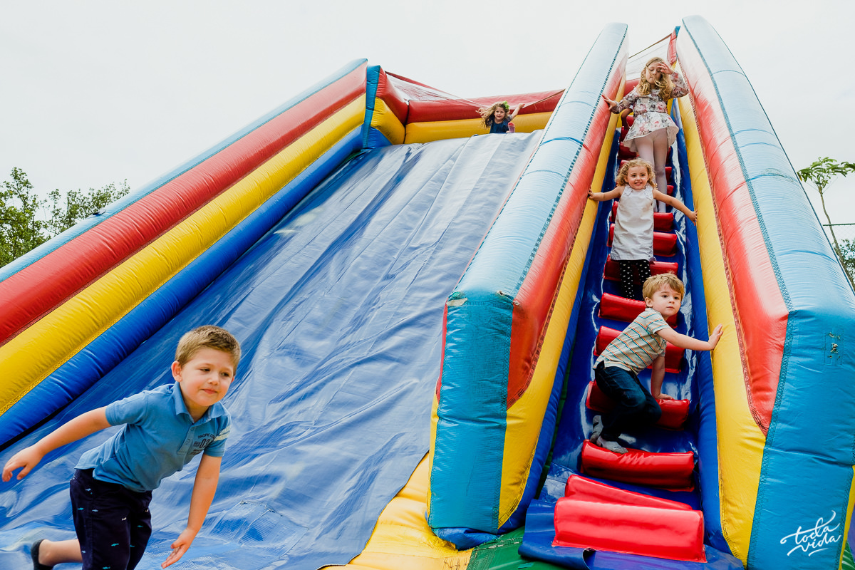criançada toda reunida no escorregador inflável da festa infantil