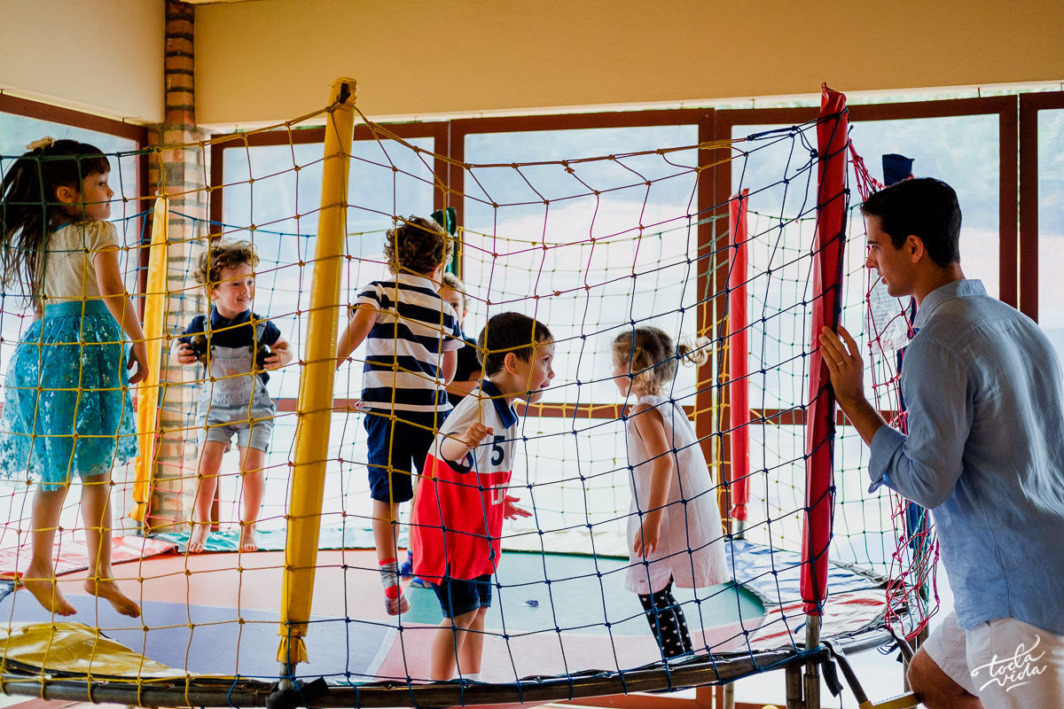 papai supervisionando o filho que se diverte no pula pula na sua festa de aniversário