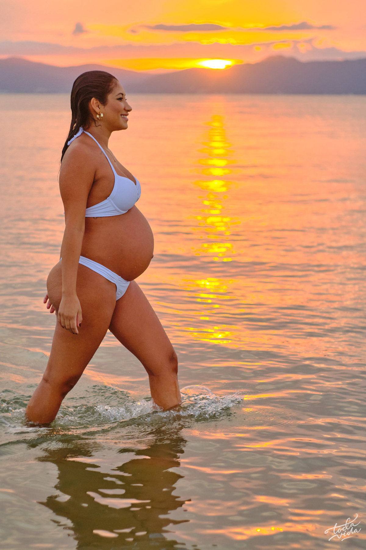 grávida posando para foto no entardecer. por-do-sol na praia da Daniela