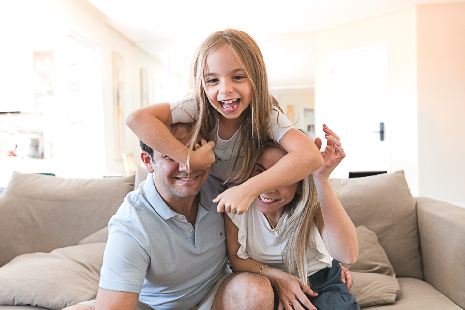 pais e filha brincando no sofá