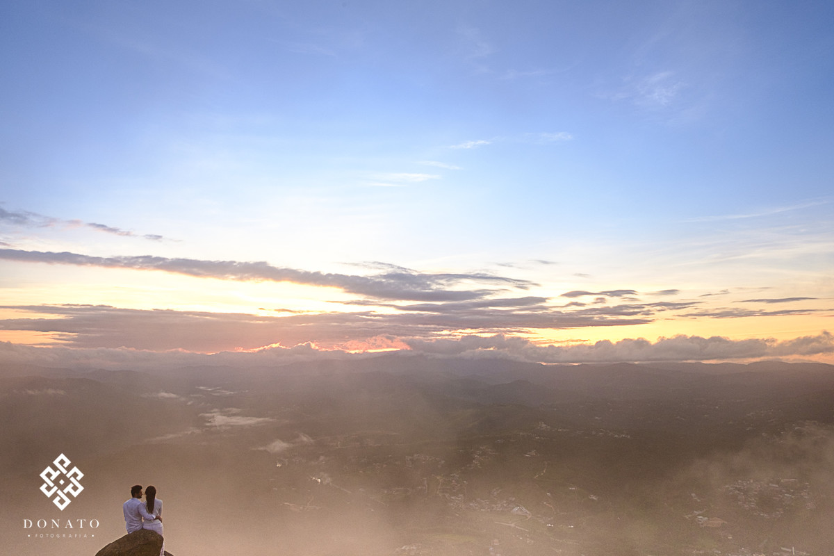O sol nascendo ao fundo e o casal a frente em uma linda paisagem.