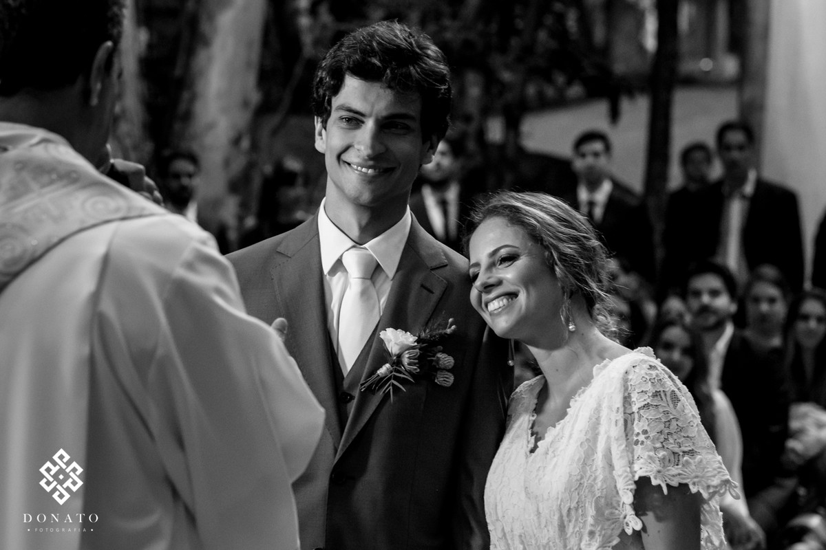 Noivos sorri, ao escutar a celebração do pastor.