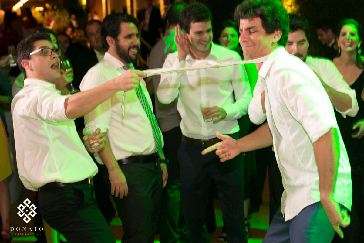 Padrinhos pegam e puxa a gravata do noivo.