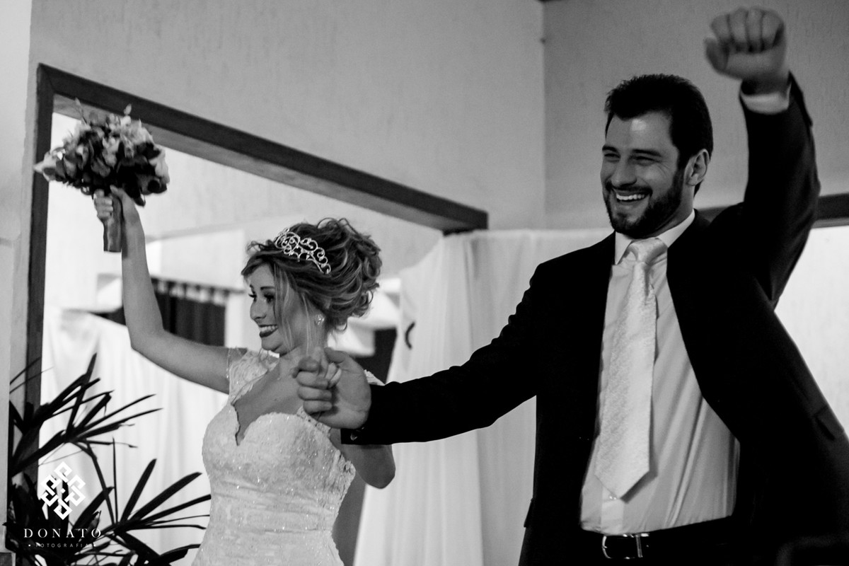 Noivos entram na festa de casamento comemorando