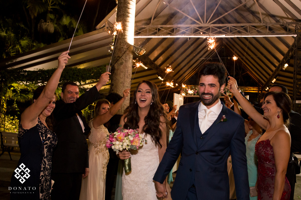 Noivso saem da cerimonia bem alegres.