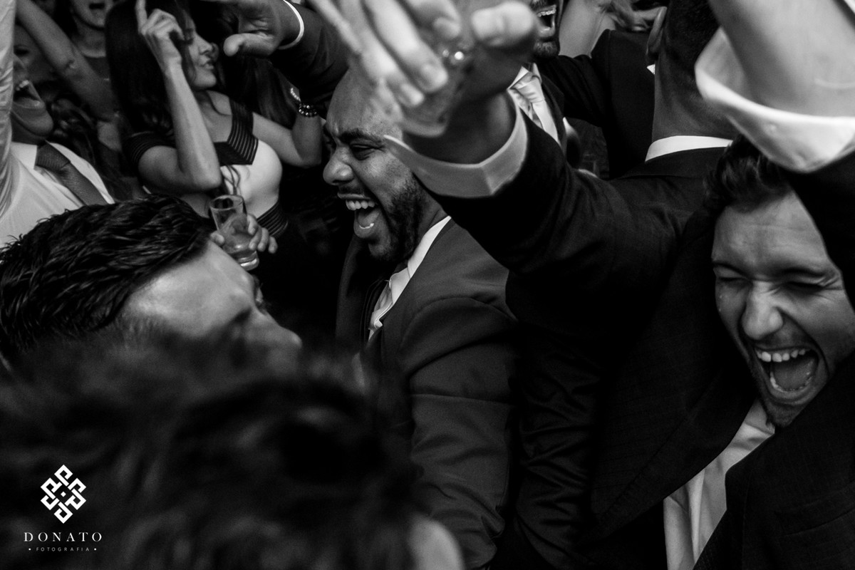 Amigos do noivo gritam e cantam a musica.