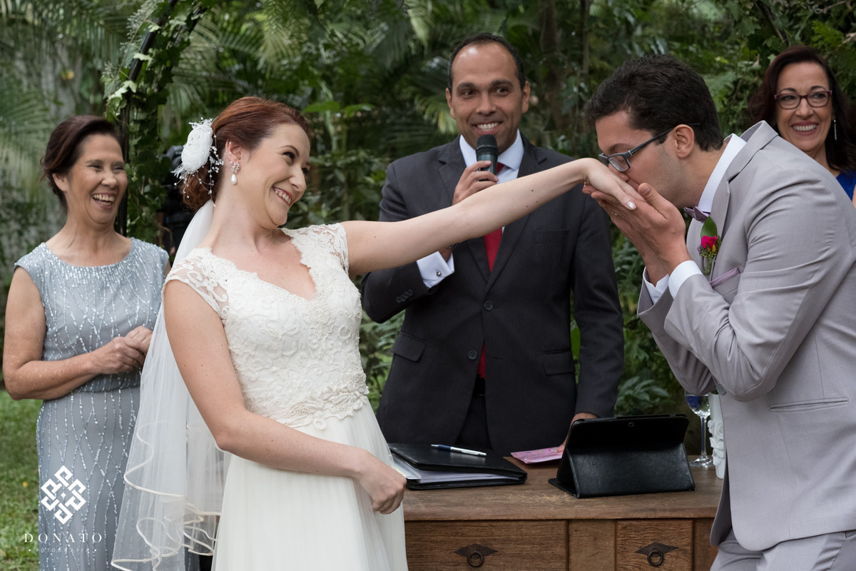 Noivo beija a mão da noiva após colocar aliança.