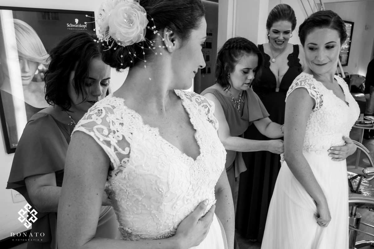 Amigas colocam o vestido na noiva.