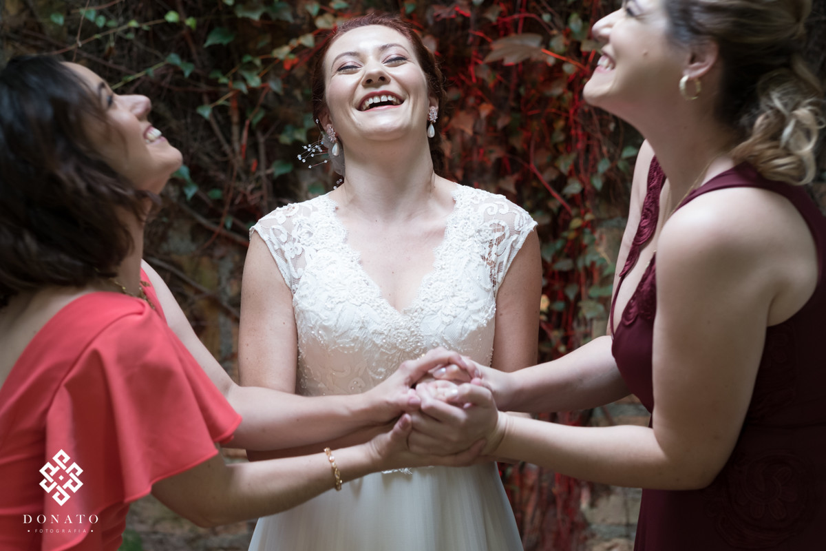 Amigas e a noiva respiram fundo de mãos dadas.