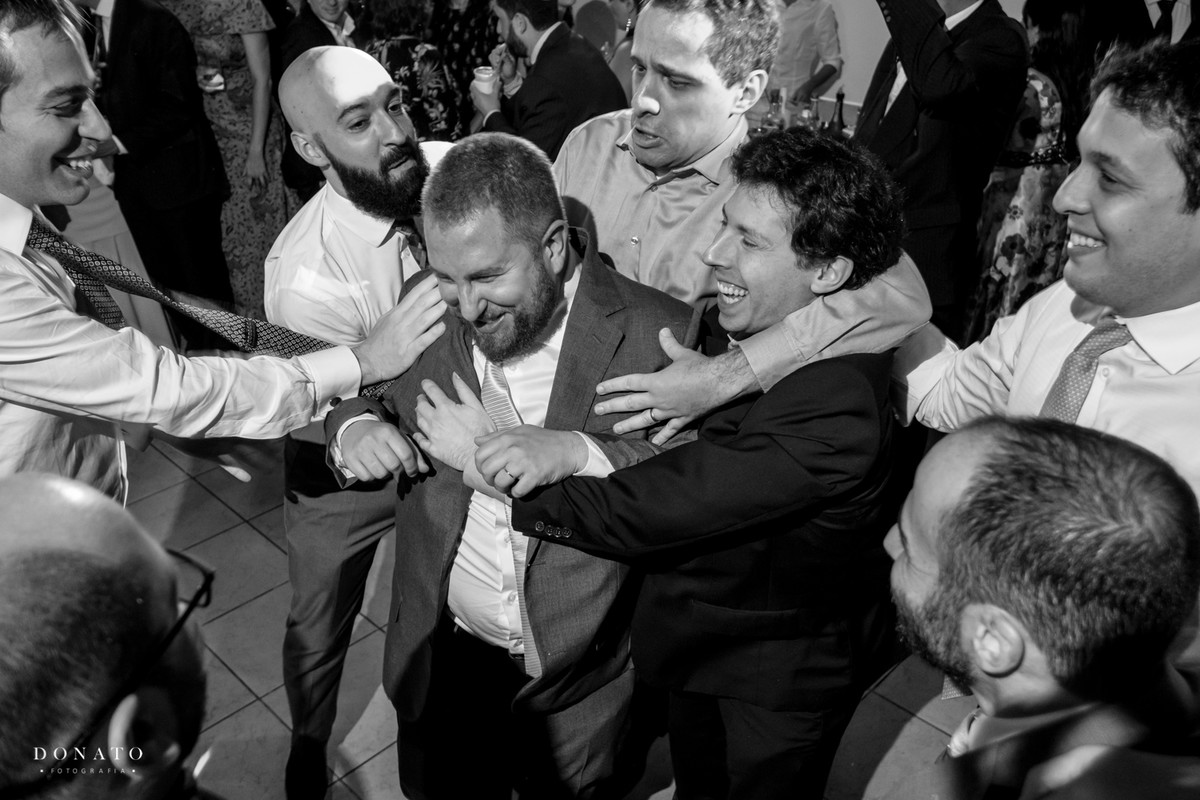 Convidados agarram o noivo, em um das tradiçoes do casamento judeu.