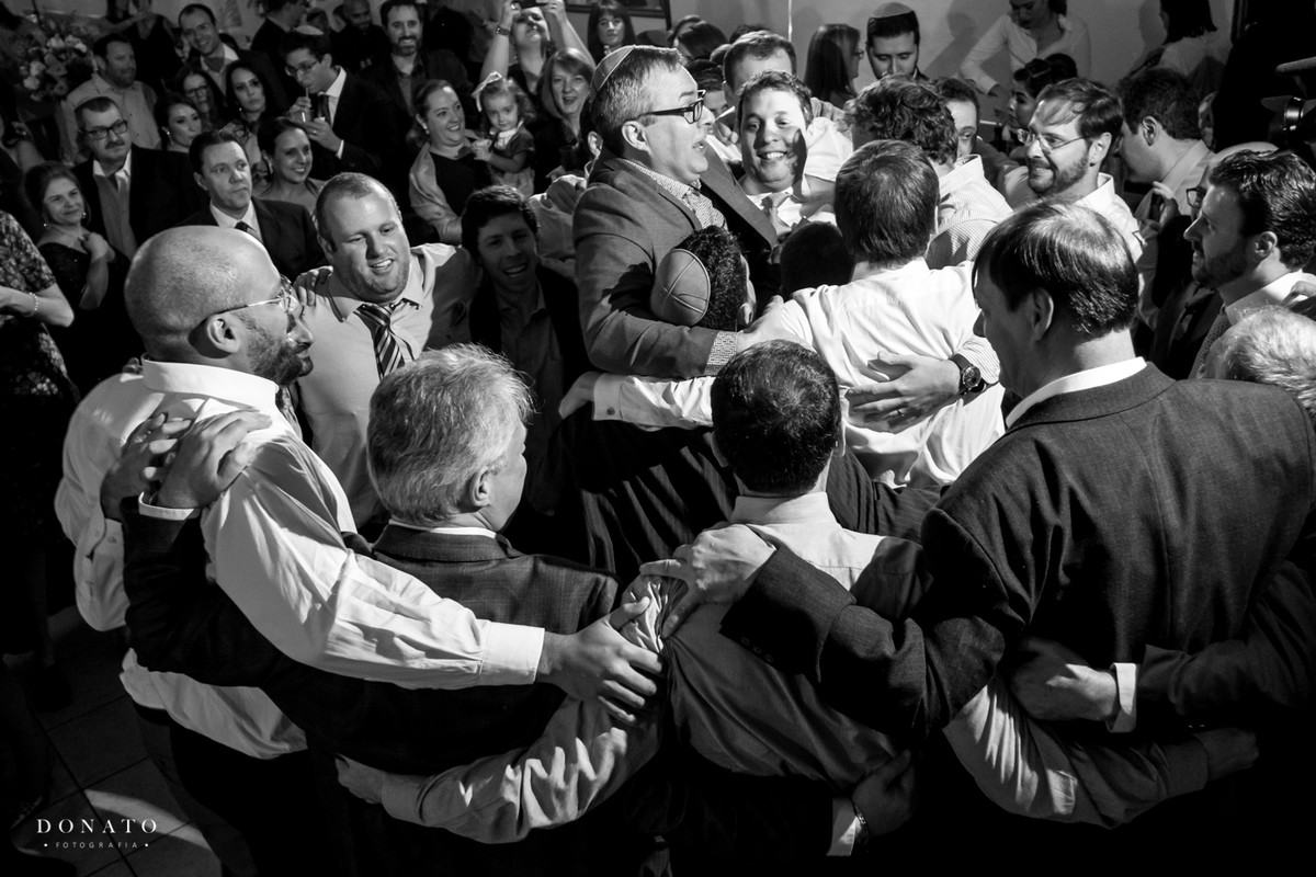 Os amigos agarram o noivo no meio da festa.