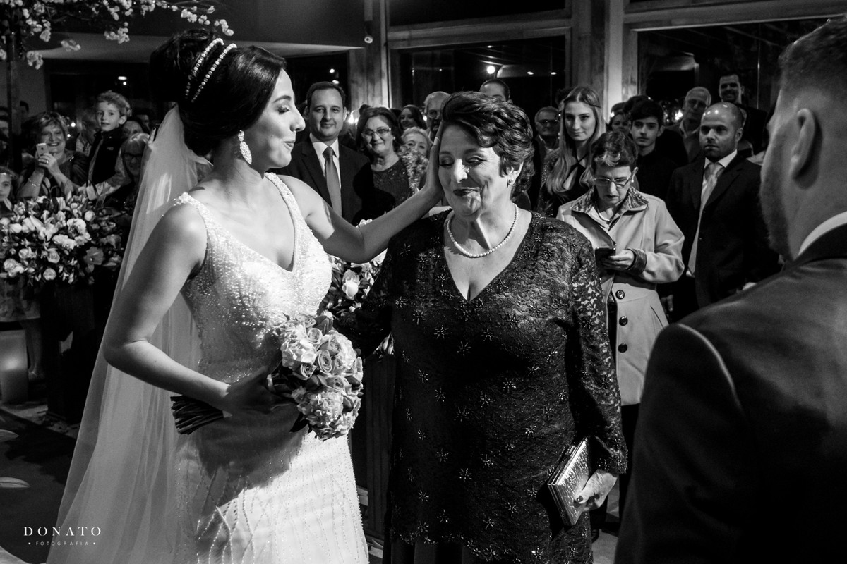 Noiva faz carinho na mae na entrada do altar.